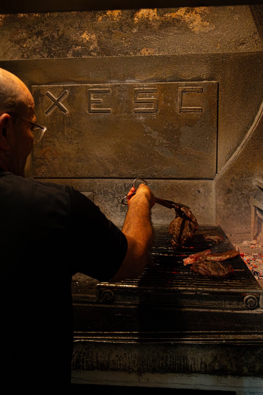 El asador colocando la carne sobre las brasas