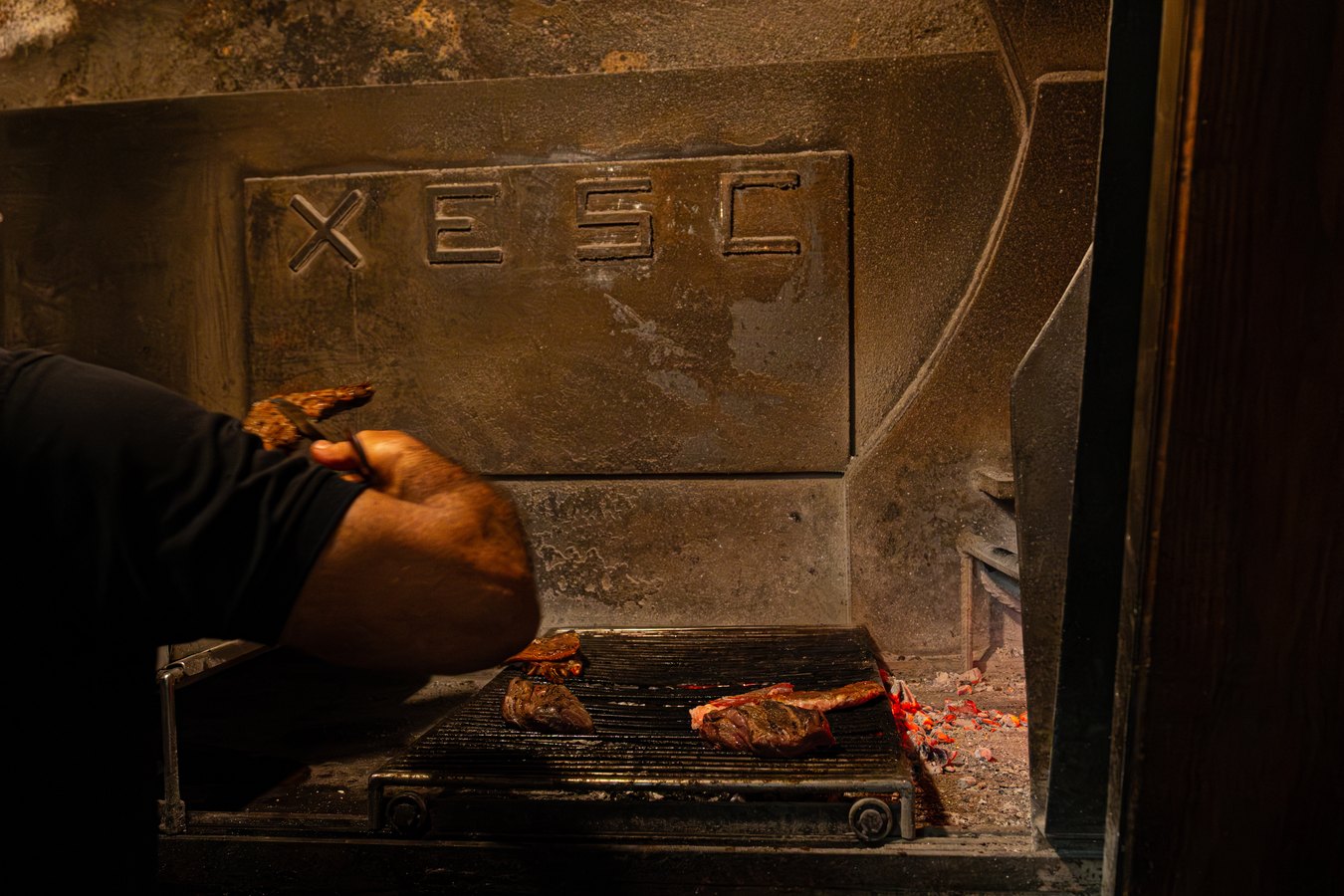 Carne haciéndose en la parrilla de leña del celler