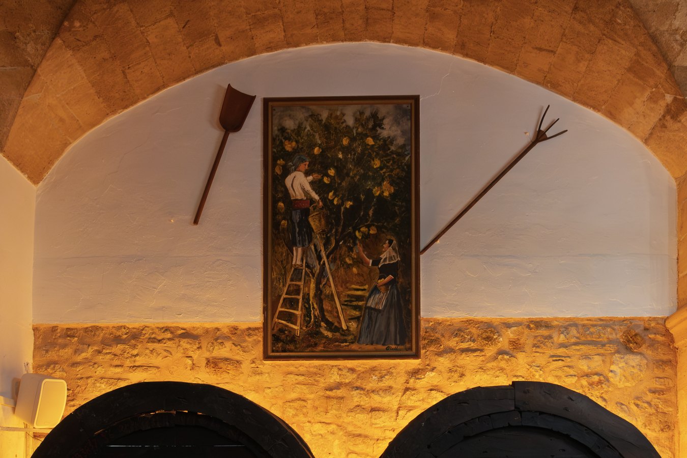 Cuadro y aperos de labranza sobre las botas de vino