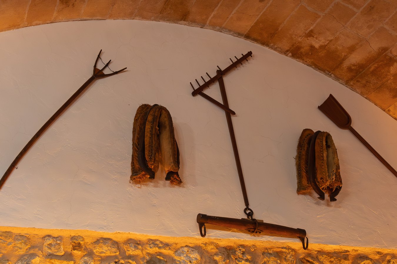 Aperos de labranza colgados en la pared encalada