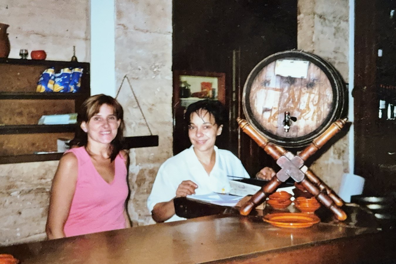 Fotografía antigua: dos trabajadoras en la barra, con la bota de vino al fondo